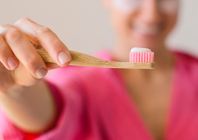 front view defocused woman with eye patches holding toothbrush 1